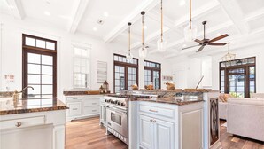 A spacious kitchen with a large island, white cabinetry, and a central stove.