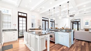 A spacious kitchen with white cabinetry, a large island, and a dining area with a gray sofa.