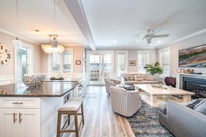 A spacious living area with a kitchen island, a dining table, and a fireplace. - Heart of OCNJ! 5BR/4BA Beach Block Condo w/ Elevator -Sleeps 16! (Ocean City)