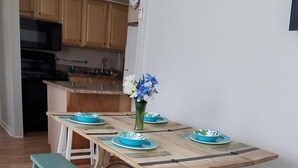 A dining area with a wooden table, blue and white plates, and a vase of flowers. - Charming Beach block getaway! Leave your sheets, towels at home! You're on VACA! (Brigantine)