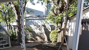 A wooden swing chair with floral cushions, a chain, and a stone pathway in a backyard. - Charming Beach block getaway! Leave your sheets, towels at home! You're on VACA! (Brigantine)