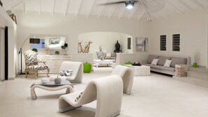 Un salón amplio con muebles modernos, un techo alto y un ventilador grande.