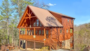 A wooden cabin with a balcony, a staircase, and a porch. - Free Tickets | Secluded Spacious Cabin w/Mountain View, Hot Tub & Game Room (Sevierville)