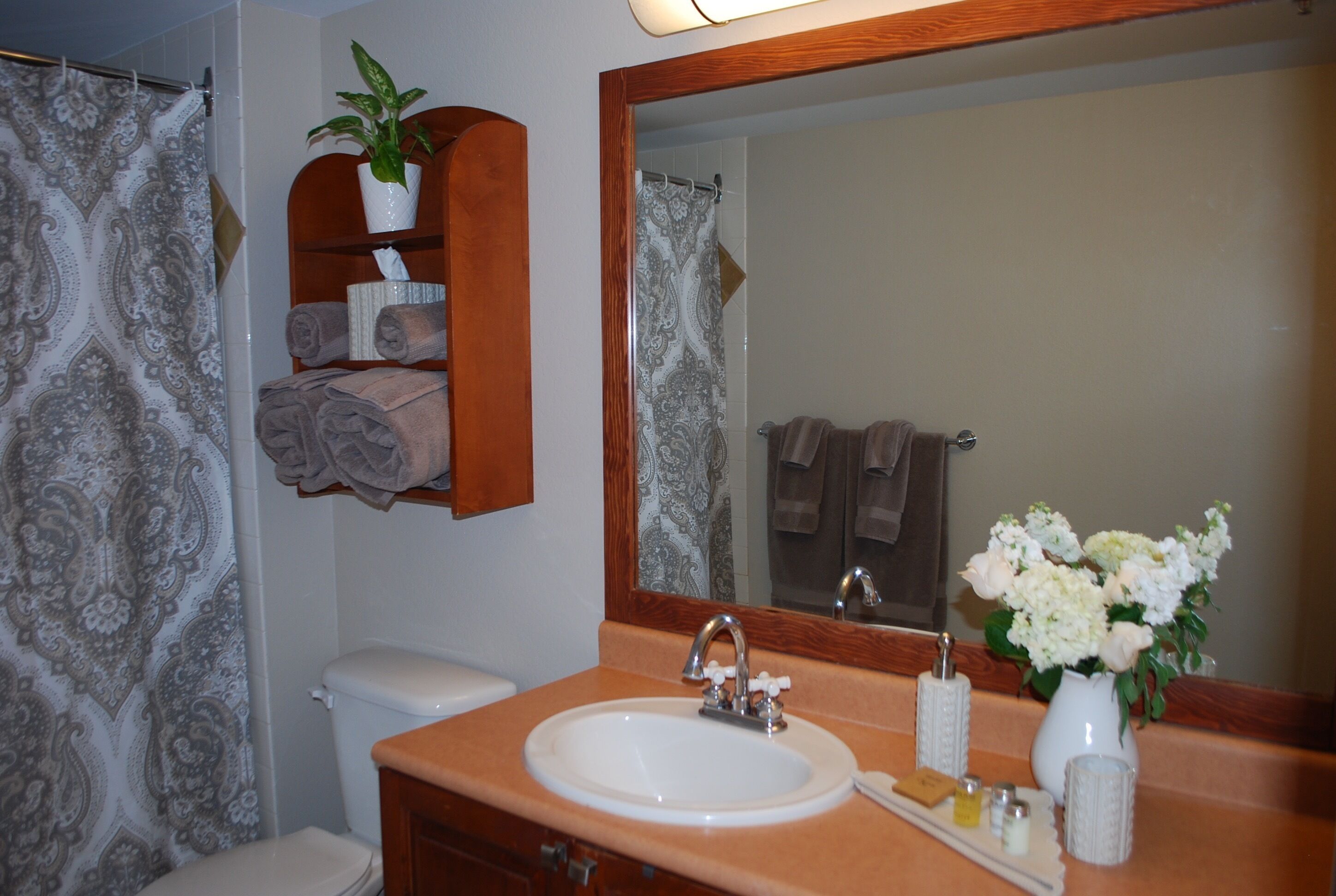 A bathroom with a sink, mirror, towel rack, and a potted plant.