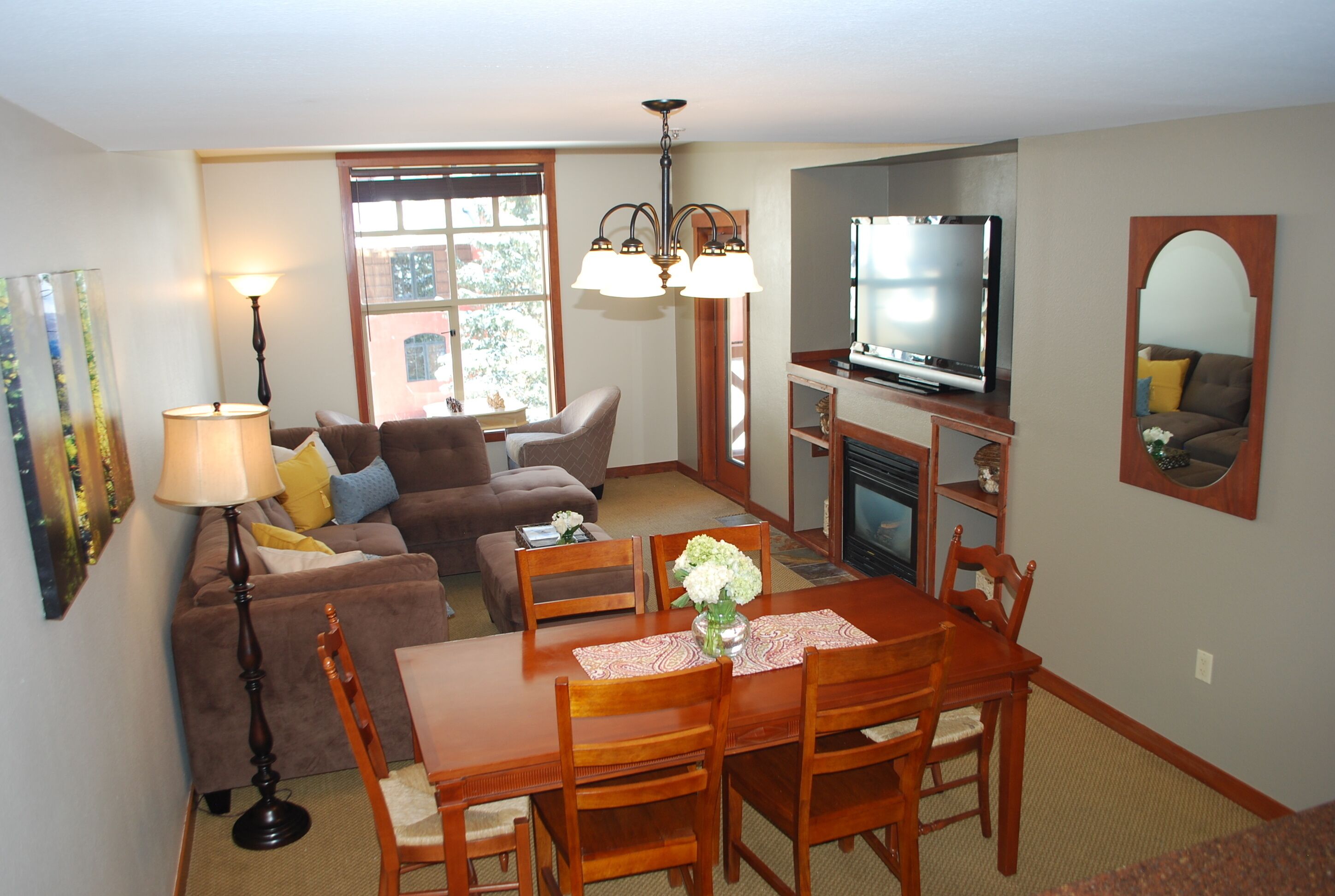 A living room with a sofa, a dining table with chairs, a TV, and a fireplace.