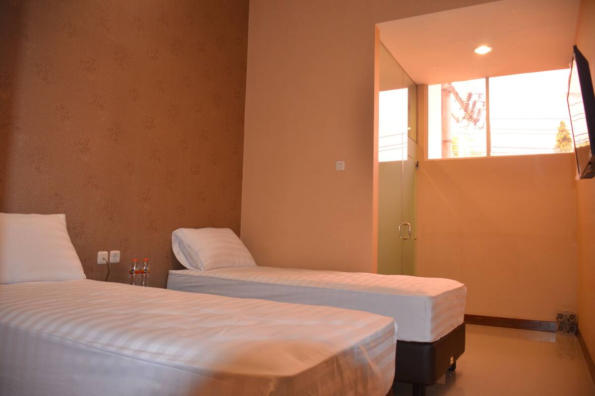 A hotel room with two beds, a window with a view, and a door leading to a bathroom.