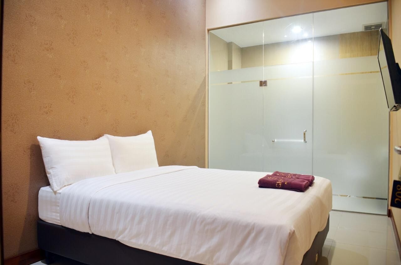 Une chambre d’hôtel avec un lit, une armoire et un miroir.
