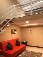 Un interior moderno con un sofá rojo, una escalera y una pequeña mesa con un adorno.