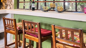 A room with a large window, wooden chairs, a table, and a bottle of wine. - Hokhmah Heart Hotel (Puerto Morelos)