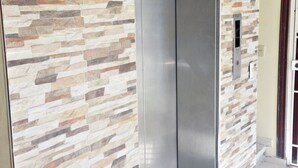 An elevator with a stone-patterned wall and a green mat at its base. - Cozy Seaview Apartment Santo Domingo (Santo Domingo)