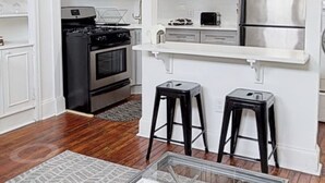 Una cocina moderna con armarios blancos, electrodomésticos de acero inoxidable y una barra con taburetes.