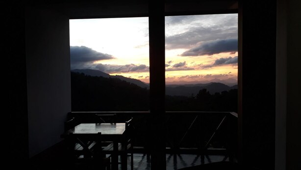 Una habitación con vistas a una puesta de sol sobre un paisaje montañoso.
