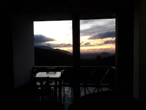 Una habitación con vistas a una puesta de sol sobre un paisaje montañoso.