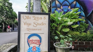 Señal de Villa Lotus 8 Yoga Studio Restaurante, con un logotipo y un mural de fondo.