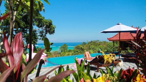 A poolside area with a view of the ocean, surrounded by tropical plants. - Bukit Permata Lembongan (Lembongan Island)
