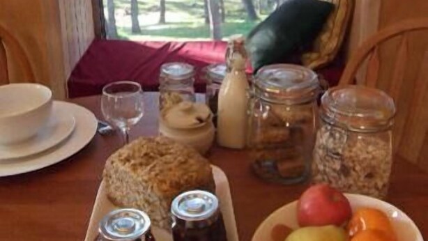 A breakfast table with bread, fruits, and condiments.