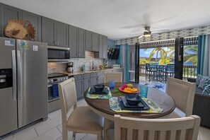 A modern kitchen with grey cabinets, stainless steel appliances, and a dining area with a round table and chairs.