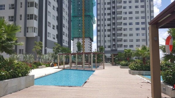 Enjoy a refreshing swim in the rooftop pool surrounded by lush greenery and a pergola.