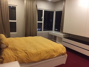 Relax in a spacious room with a large bed, city view, and comfortable seating area.