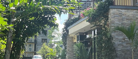 Ein Hotel Eingang mit einem Schild, auf dem 'HOTEL GLORY GARDEN' steht, umgeben von üppigem Grün und einer gepflasterten Auffahrt.