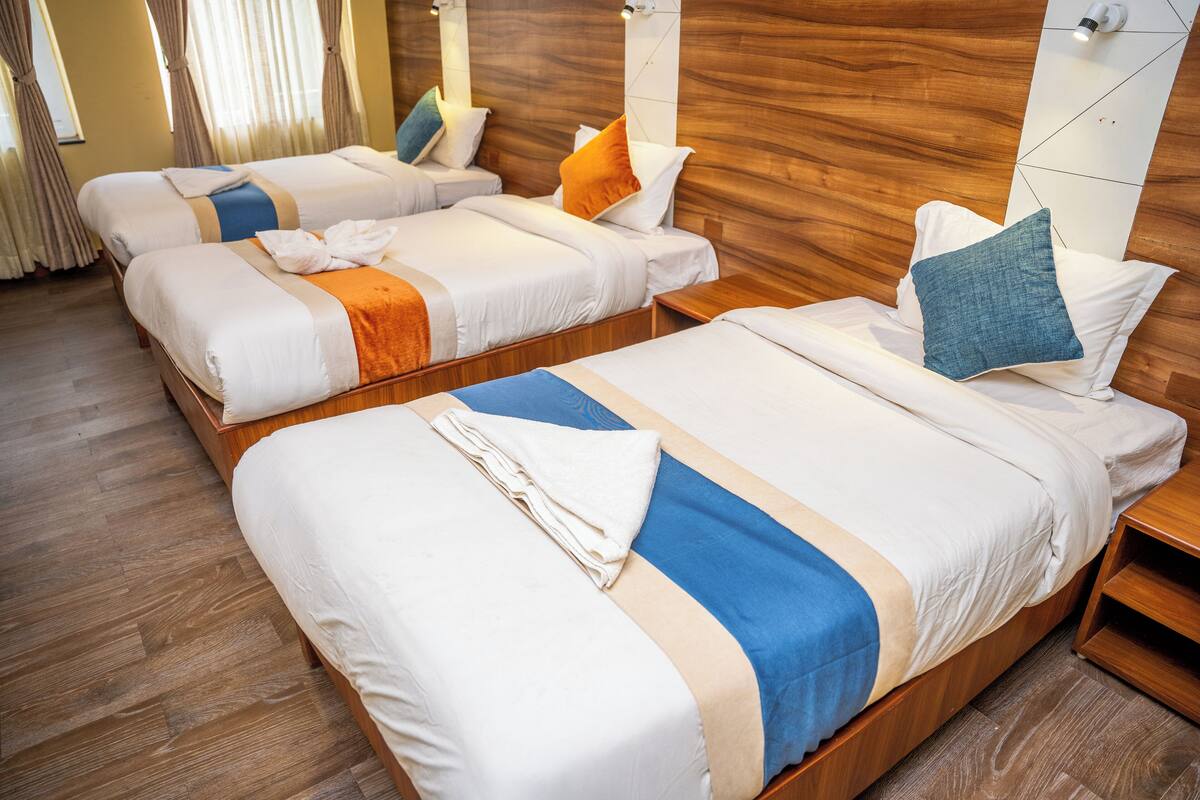 A hotel room with two beds, wooden headboards, and a wooden floor.