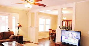 A living room with a television, sofa, coffee table, and a ceiling fan.