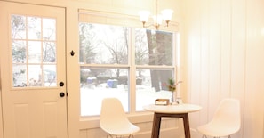 A breakfast nook with a white door, large windows, and a wooden floor.
