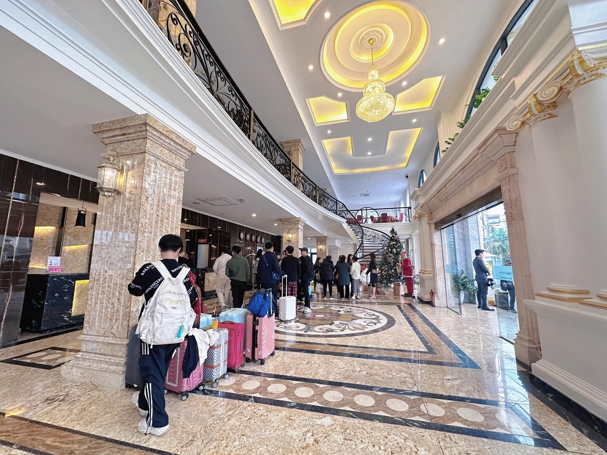 A hotel lobby with marble flooring, a grand staircase, and a Christmas tree.