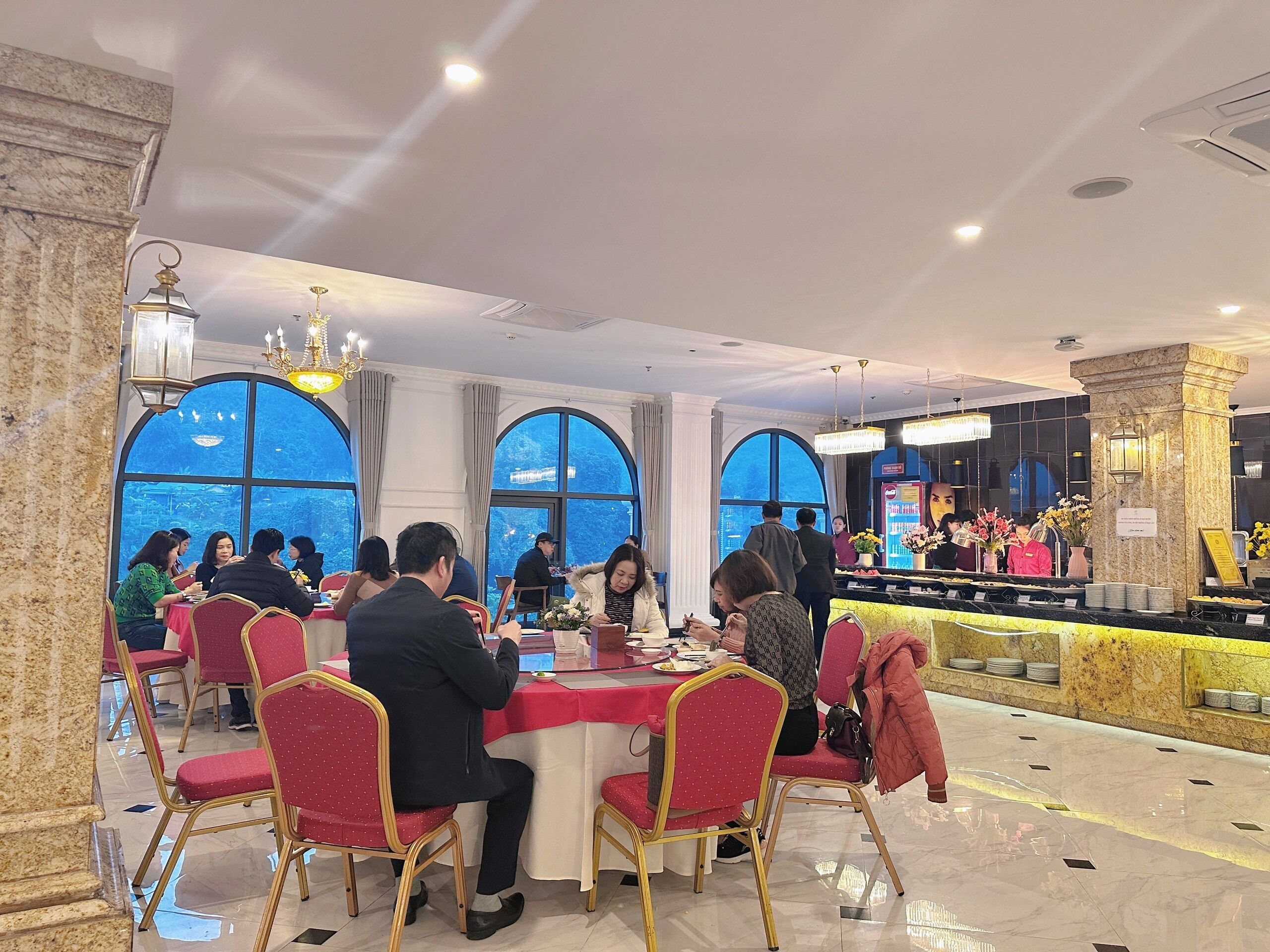 Un restaurante con amplias ventanas de arco, columnas de mármol y una barra de mármol.