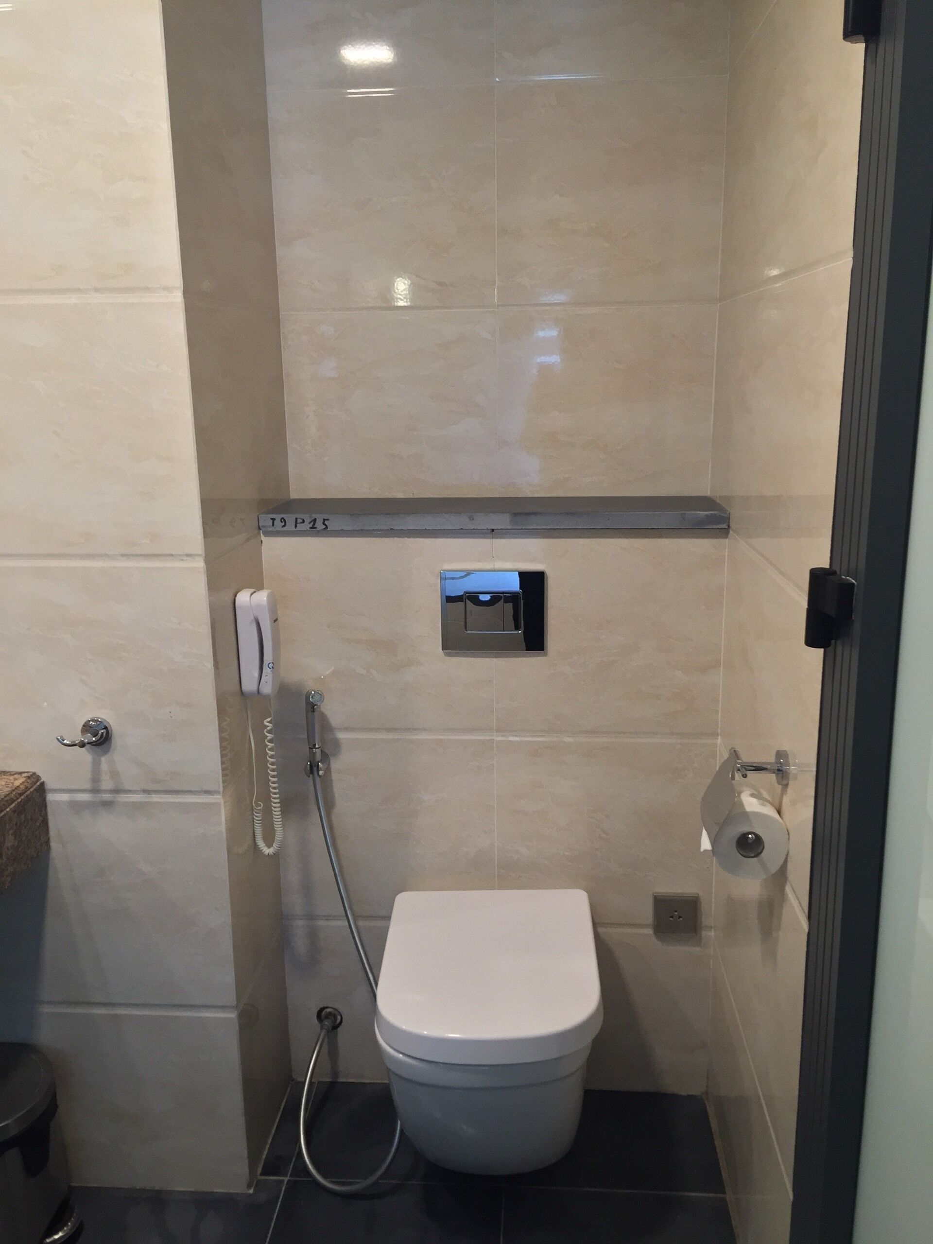 A small, modern bathroom with a toilet, a hand dryer, and a paper towel dispenser.
