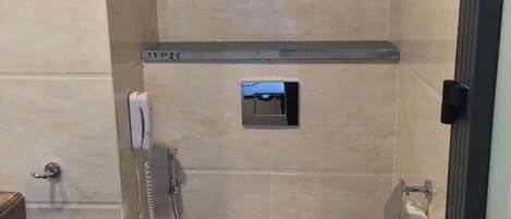 A small, modern bathroom with a toilet, a hand dryer, and a paper towel dispenser.