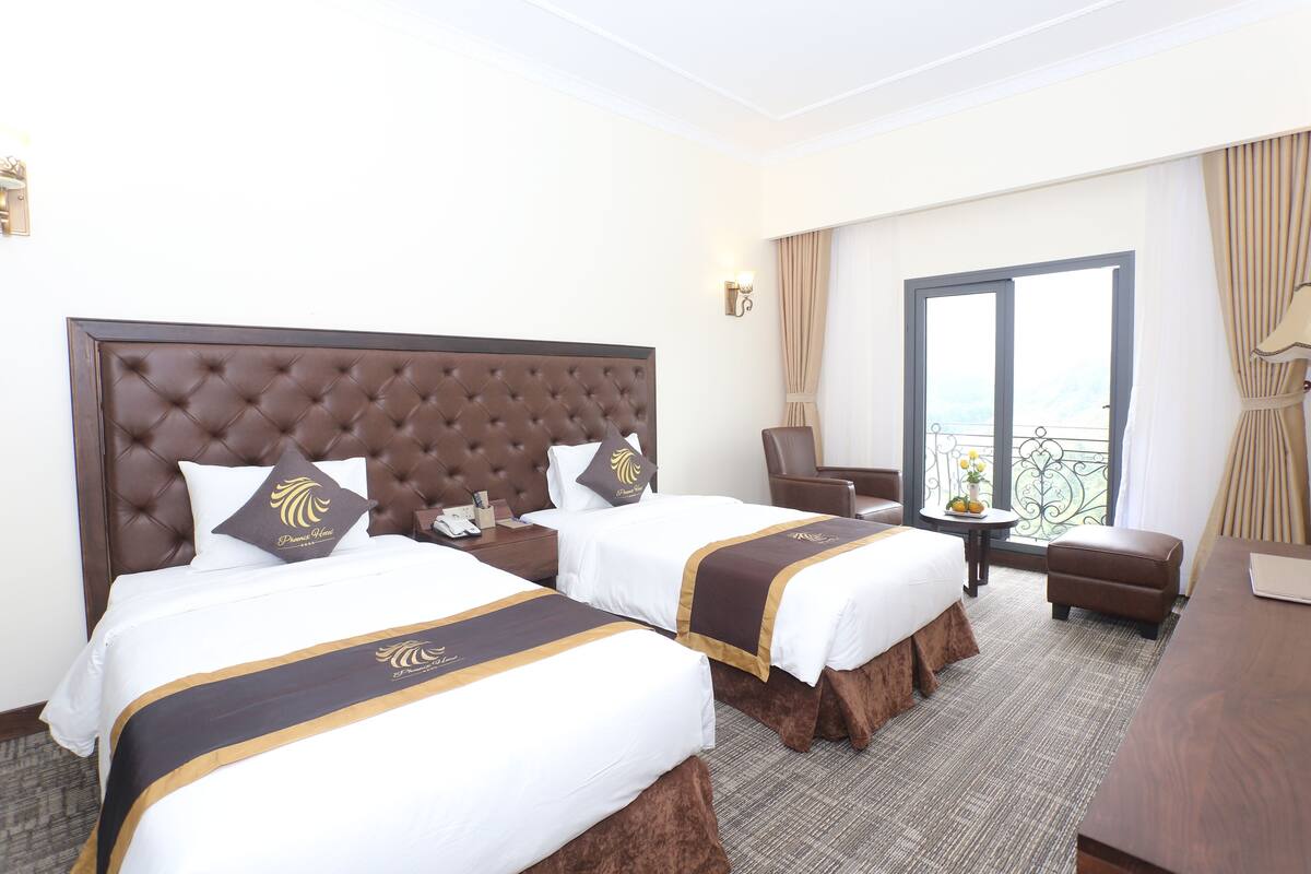Une chambre d’hôtel avec deux lits, un canapé, une petite table et un balcon avec vue.