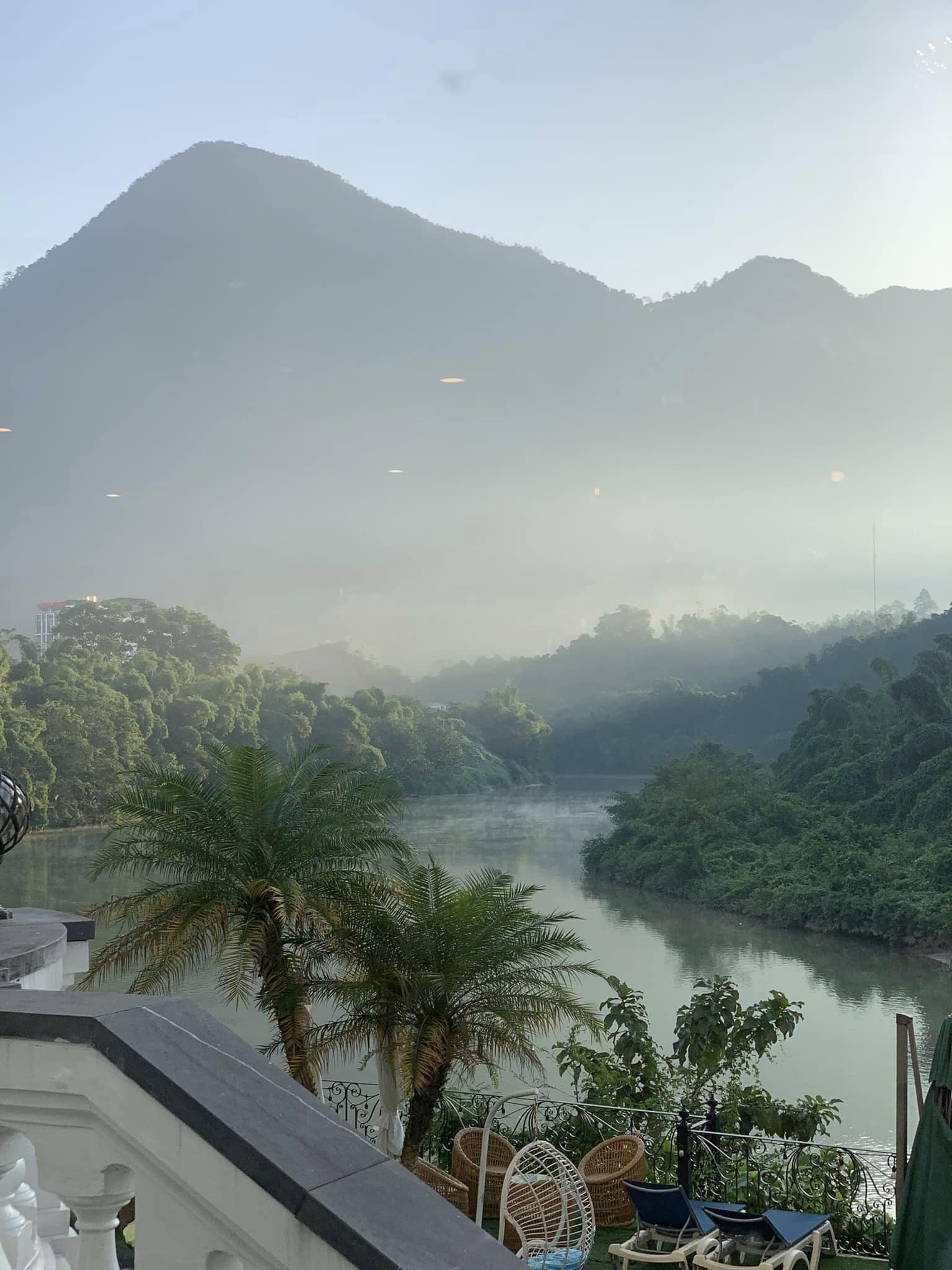 A view of a river with surrounding greenery and mountains in the background.