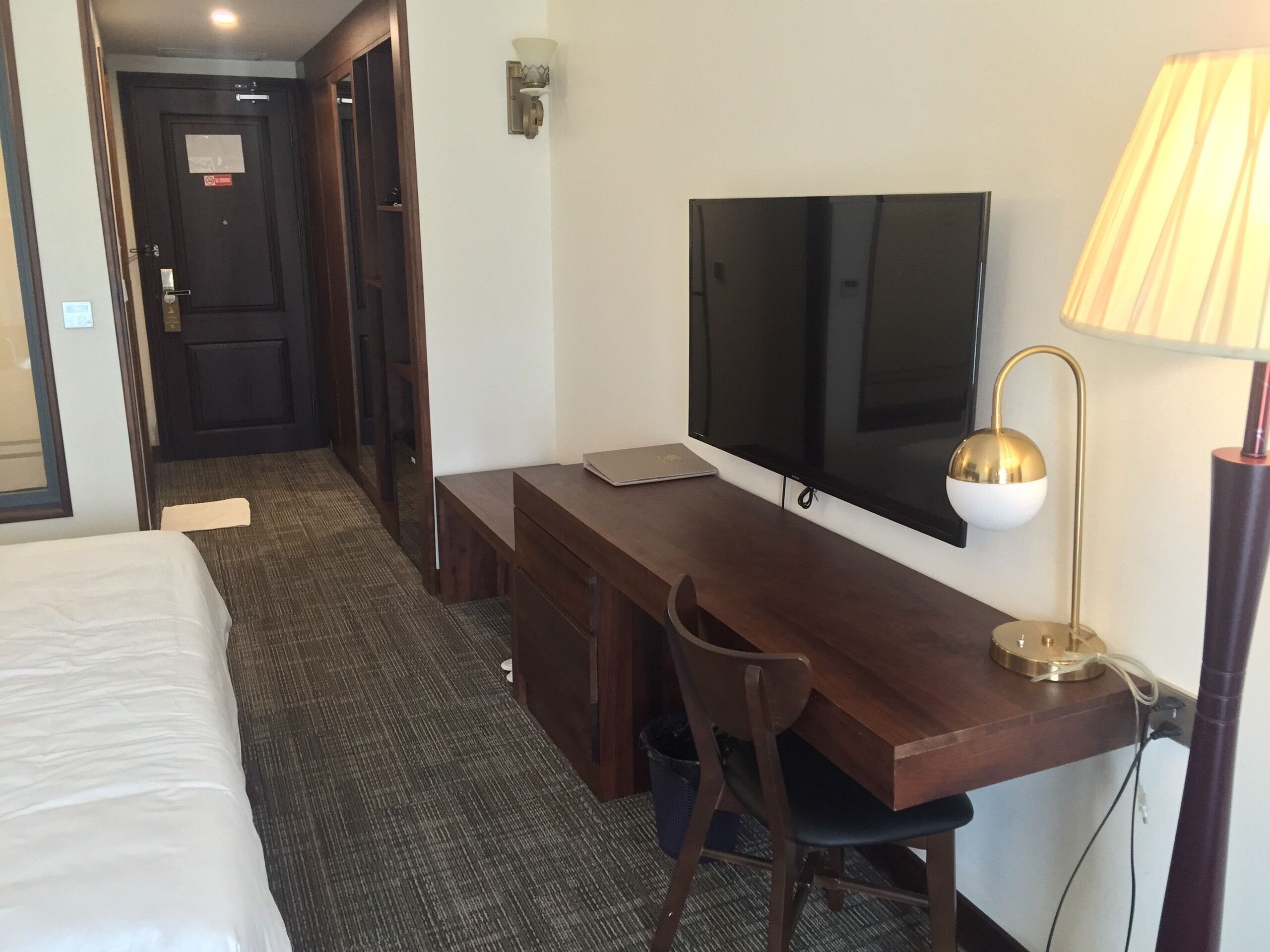 Une chambre d’hôtel avec un lit, un bureau équipé d’une télévision, une lampe et une chaise.