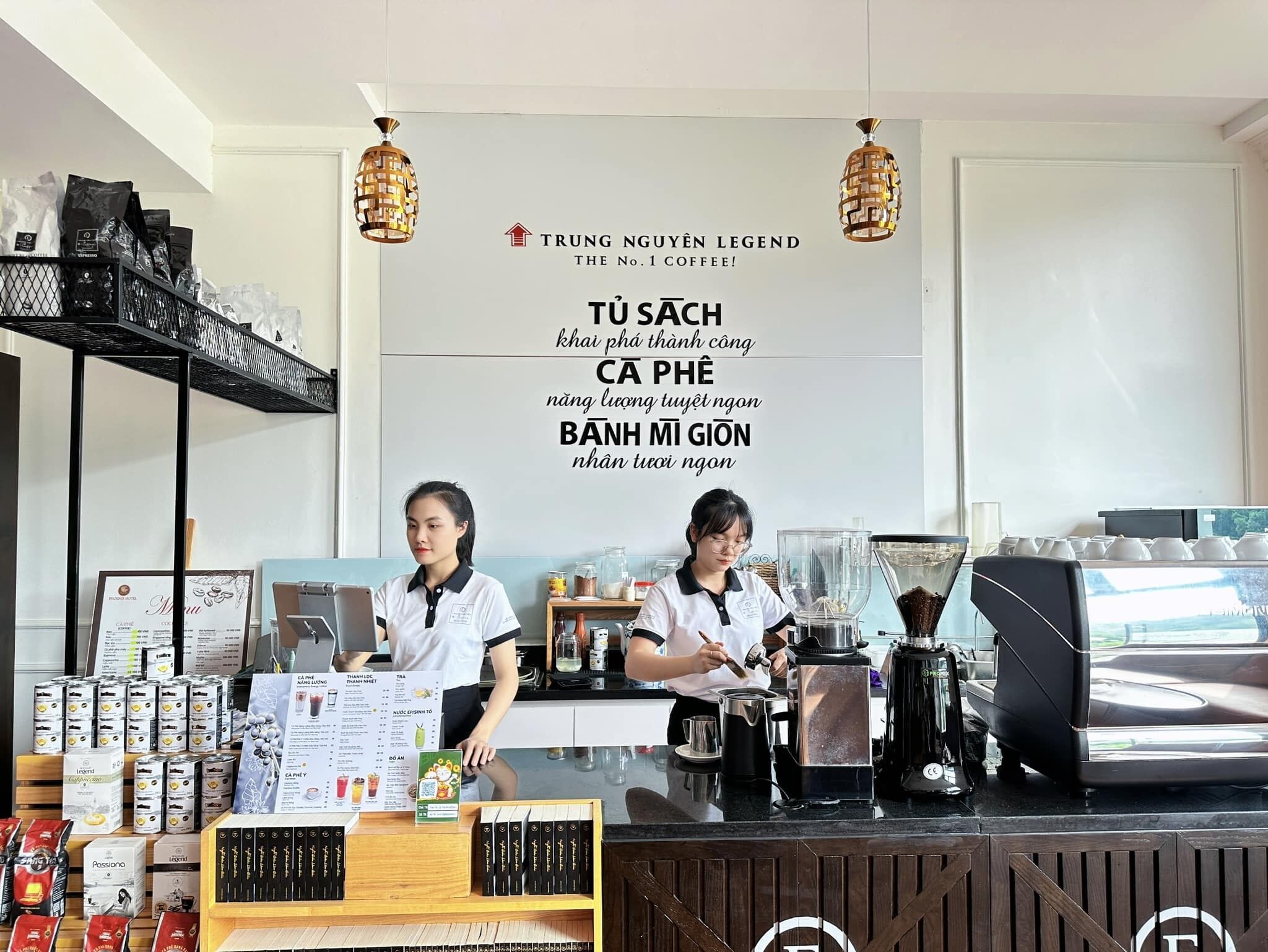 A coffee shop interior with two baristas at work, a menu board, coffee-making equipment, and a display of coffee products.