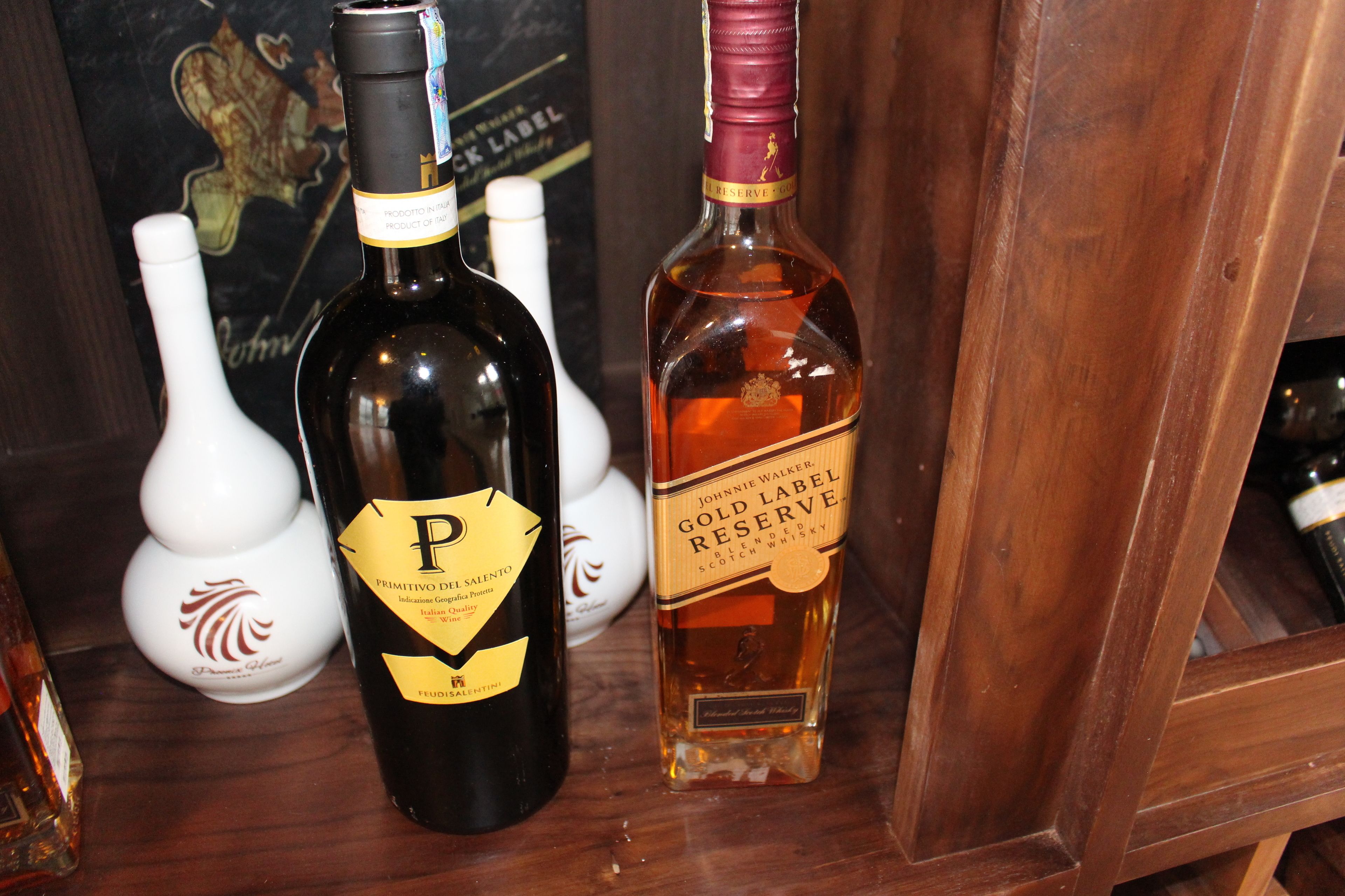 Dos botellas de alcohol sobre una repisa de madera.