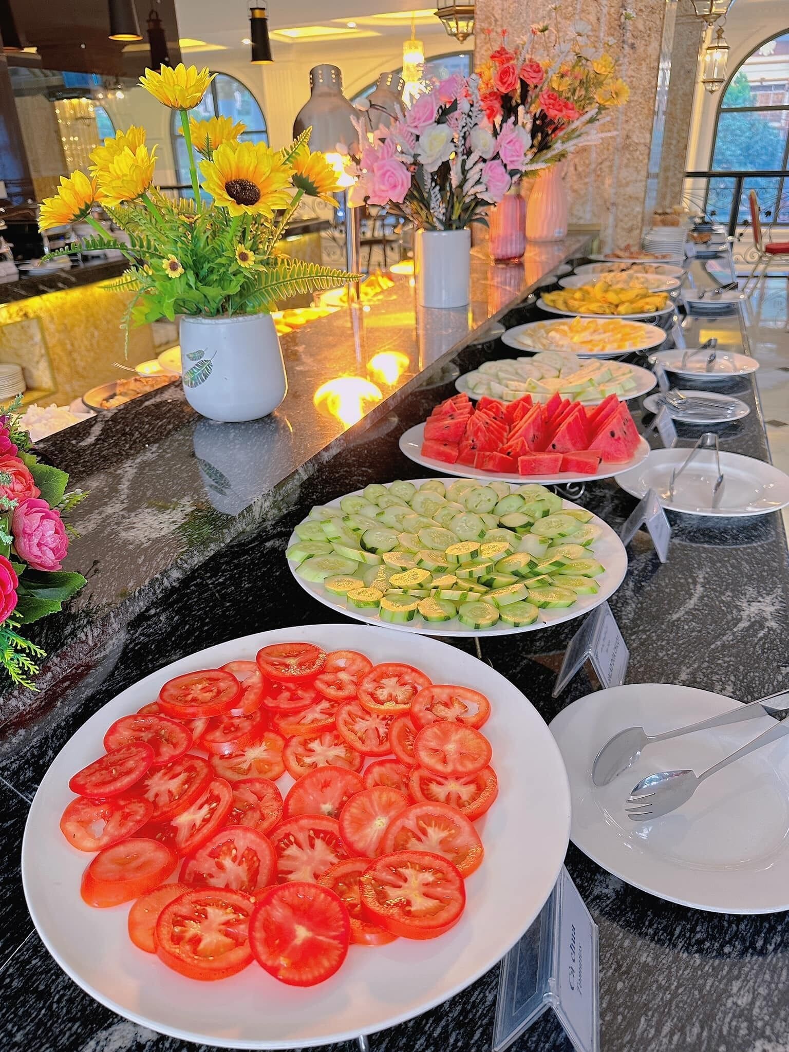 A buffet with various food options including watermelon, cucumber salad, and tomato slices.