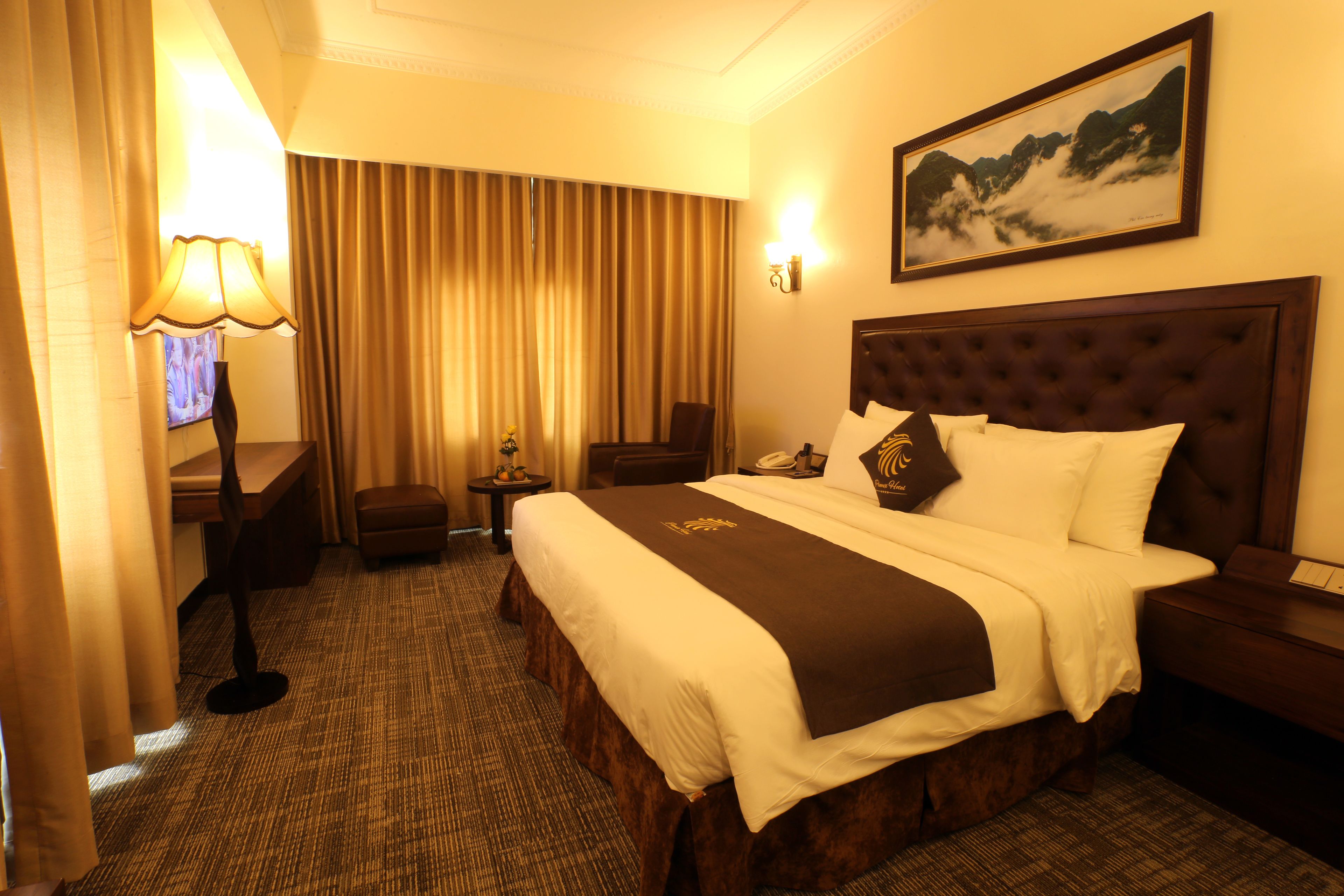 Ein Hotelzimmer mit einem großen Bett, einem Schreibtisch, einem Stuhl und einer Lampe.