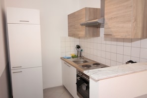 A compact kitchen with white cabinets, a stainless steel sink, and a built-in oven.