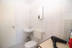 A small bathroom with a toilet, sink, and a hairdryer on a table.