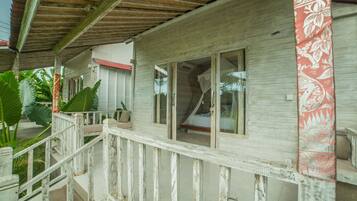 Une villa en bois dotée d’un balcon, de grandes fenêtres et d’un rideau rouge à motifs.