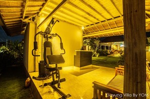Un espacio al aire libre techado con equipo de ejercicio, una recepción y un césped bien cuidado.