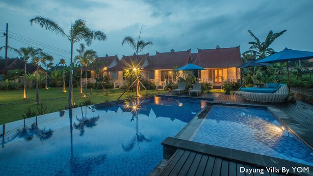 Een villa met zwembad, terras en een verzorgde tuin.