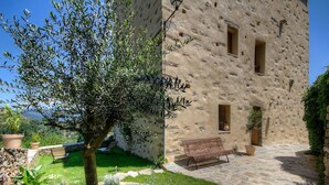 A rustic stone building with a bench and potted plants. - Castellu d'Orezza (Carcheto-Brustico)