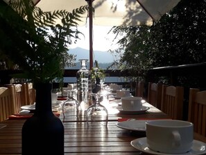 An outdoor dining area with a long table set for two, surrounded by chairs, under a canopy. - Castellu d'Orezza (Carcheto-Brustico)