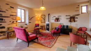 A cozy living room with stone walls, a fireplace, and red upholstered chairs. - Castellu d'Orezza (Carcheto-Brustico)