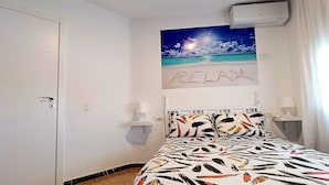 A bedroom with a bed, a painting of a beach scene, and the word "RELAX" written on the wall. - CALAFELL 5 BEACH WITH: POOL, BEACH, PARKING, SUPERMARKETS / MAC-DONALS (Calafell)