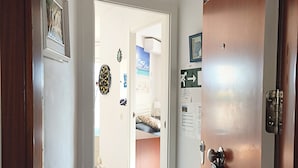 A hallway leading to a bedroom with a bed, a door with a lock, and a wall-mounted picture. - CALAFELL 5 BEACH WITH: POOL, BEACH, PARKING, SUPERMARKETS / MAC-DONALS (Calafell)