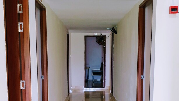 A long, narrow hallway with wooden doors on either side and a tiled floor.