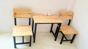 A small wooden table with four chairs, two glass jars, and a white wall.
